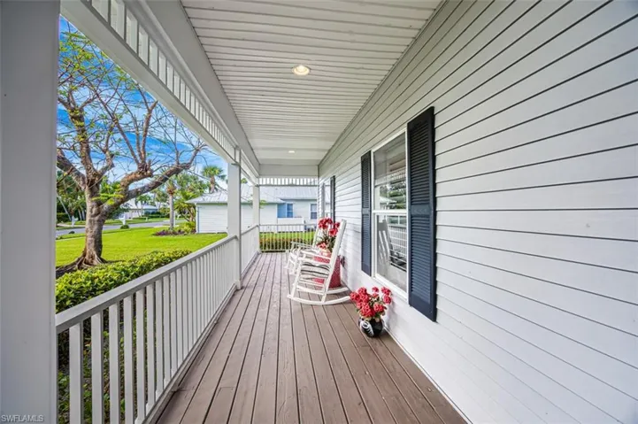 Wooden deck featuring a garage, a yard, and covered porch