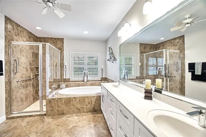 Bathroom featuring independent shower and bath, vanity, and ceiling fan