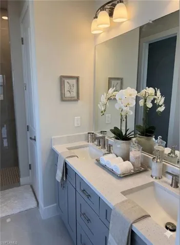 Full bathroom featuring double vanity, light tile patterned floors, and a stall shower