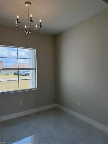 Spare room with suspended lighting and baseboards