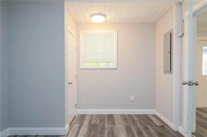 Spare room featuring wood finished floors, electric panel, wooden ceiling, and plenty of natural light