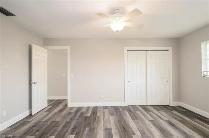 Unfurnished bedroom featuring dark wood-style floors, a closet, and ceiling fan