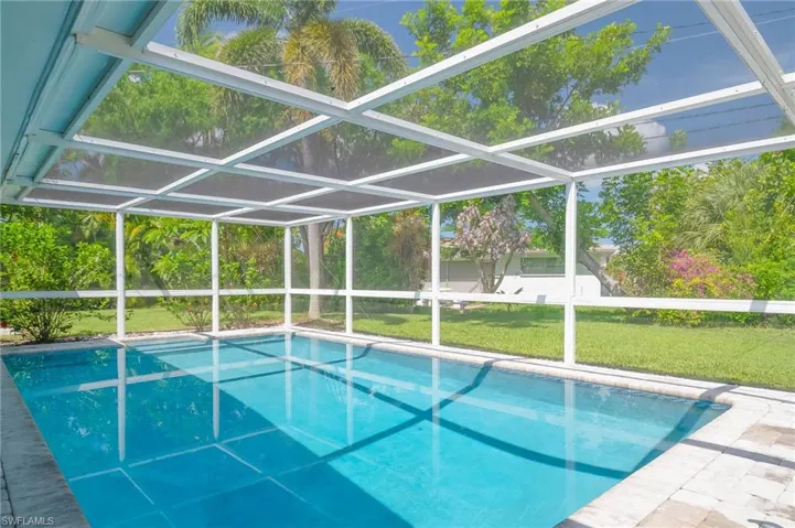 Outdoor pool featuring a yard and glass enclosure