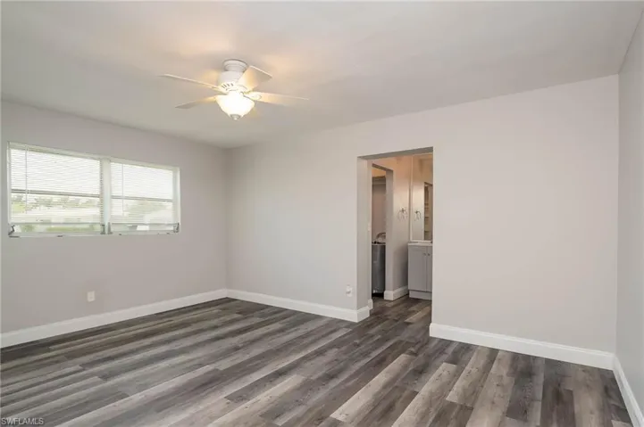Unfurnished room with a ceiling fan and dark wood-type flooring