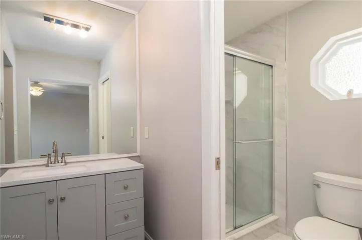 Bathroom featuring a stall shower, vanity, and a ceiling fan