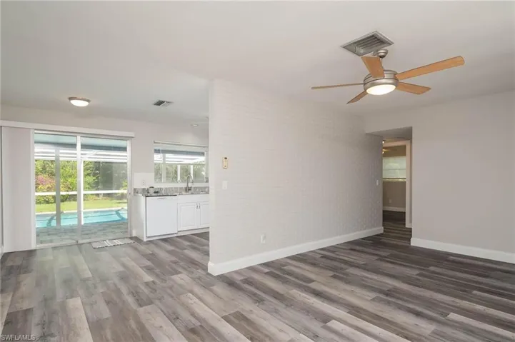 Empty room with ceiling fan, brick wall, and wood finished floors