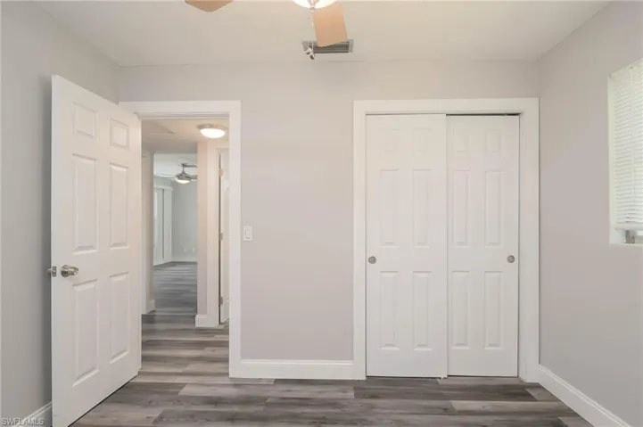 Unfurnished bedroom with dark wood-style flooring, a closet, and ceiling fan