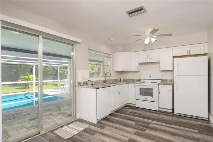 Kitchen featuring white appliances, under cabinet range hood, white cabinets, and dark wood-style floors