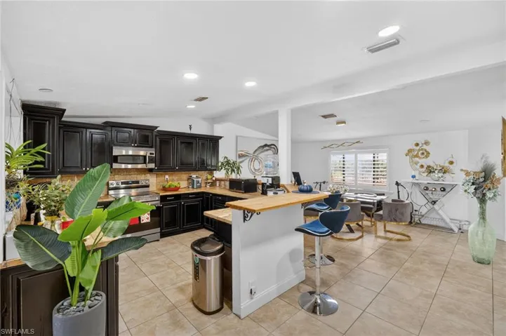 Expansive kitchen featuring dark wood cabinetry, stainless steel appliances, and wood-finish countertops