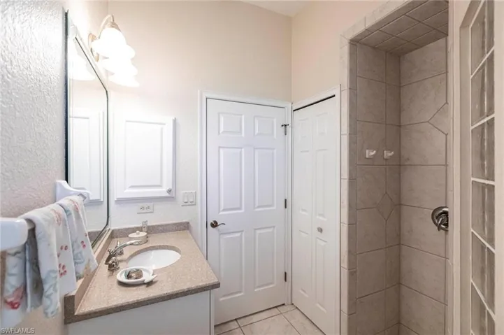 Full bath featuring vanity, tile patterned floors, a closet, and a stall shower