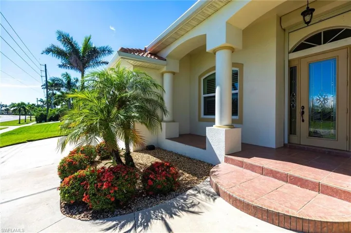 Property entrance with stucco siding, a tiled roof, and a porch