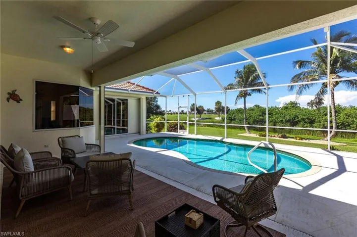 Swimming pool featuring glass enclosure, a ceiling fan, and a patio