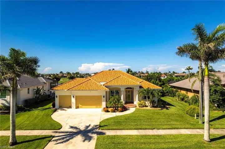 Mediterranean / spanish house with an attached garage, driveway, a front lawn, stucco siding, and a tiled roof