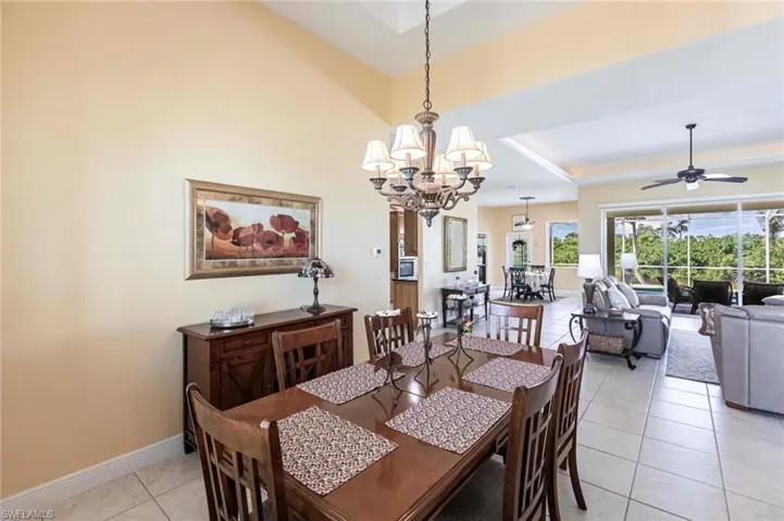 Dining area featuring light tile patterned flooring, a chandelier, a tray ceiling, and a ceiling fan