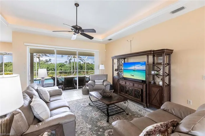 Tiled living area with a ceiling fan, a raised ceiling, and a sunroom