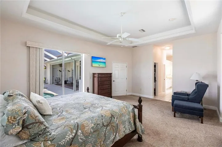 Bedroom featuring a tray ceiling, carpet flooring, and ceiling fan