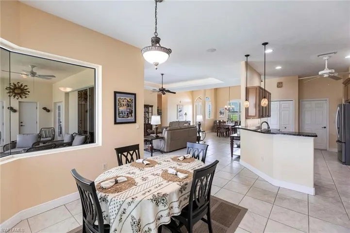 Dining space with ceiling fan, light tile patterned floors, a raised ceiling, and recessed lighting