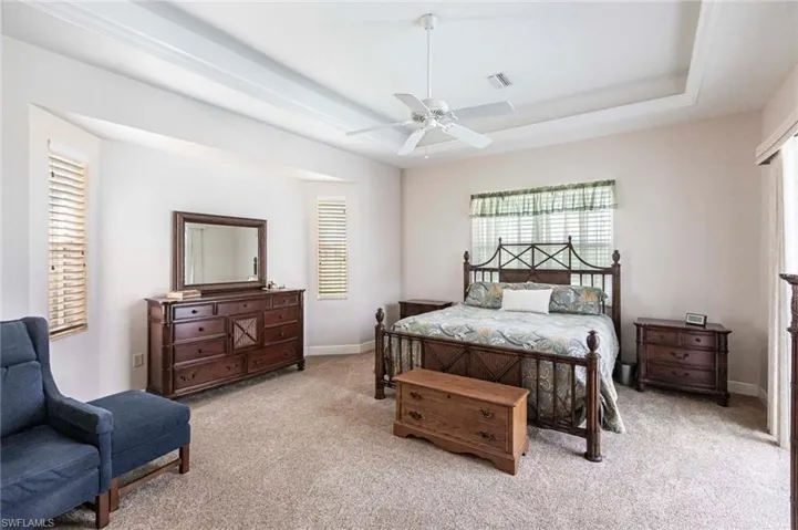 Carpeted bedroom featuring a tray ceiling and ceiling fan