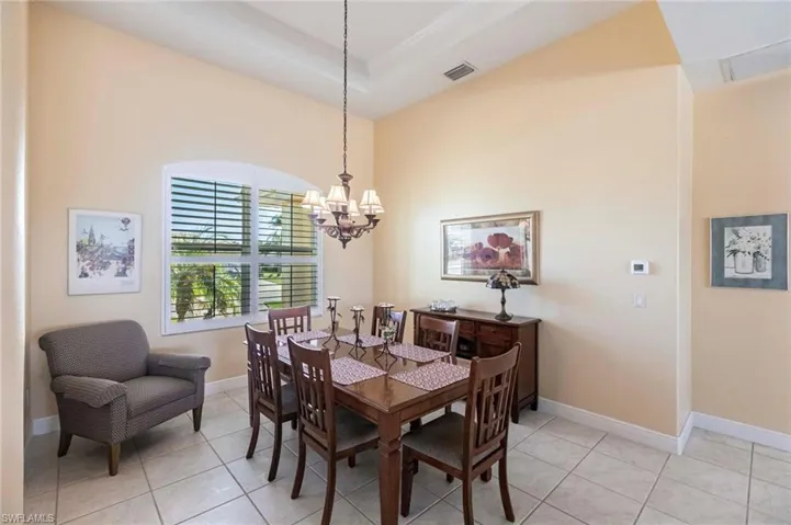Dining area featuring light tile patterned floors, a chandelier, and a raised ceiling