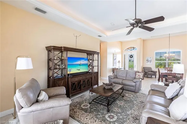 Living area with a tray ceiling, tile patterned floors, ceiling fan, and a chandelier