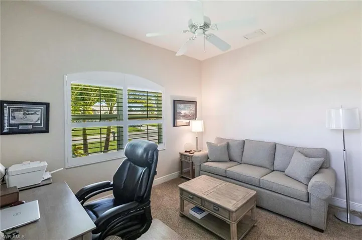 Carpeted home office featuring a ceiling fan and baseboards