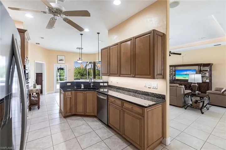 Kitchen with stainless steel appliances, light tile patterned floors, ceiling fan, a peninsula, and open floor plan