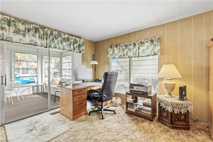 Home office with light carpet and wooden walls
