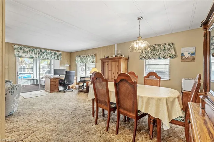 Dining room featuring a desk, a chandelier, light colored carpet, and plenty of natural light