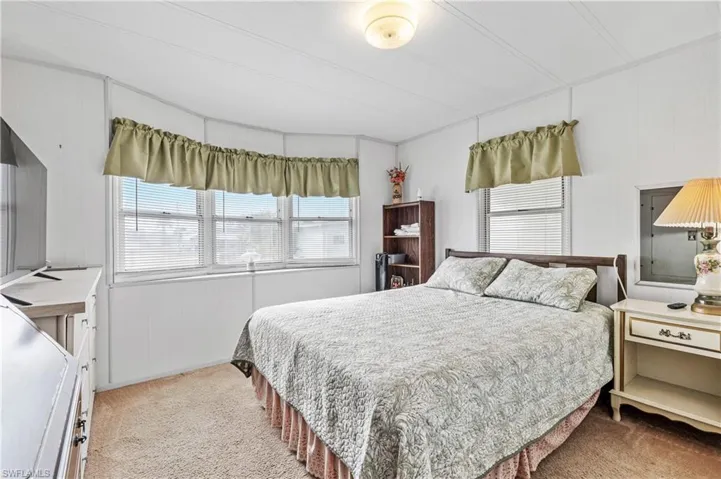 Bedroom featuring light carpet, wooden walls, and a decorative wall