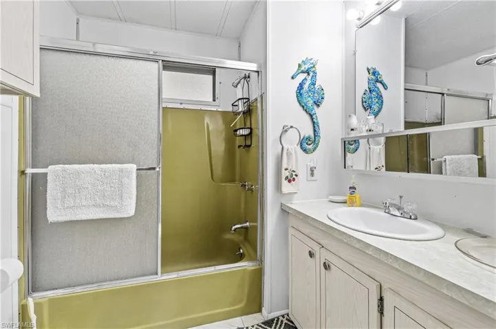 Full bath featuring shower / bath combination with glass door and vanity