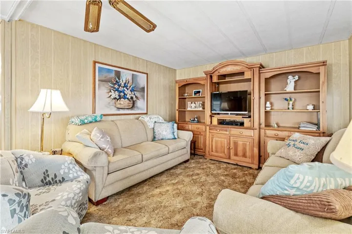 Living room with wood walls and light colored carpet