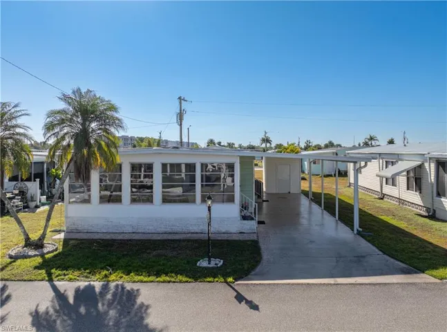 View of front facade featuring a front lawn, concrete driveway, and an attached carport