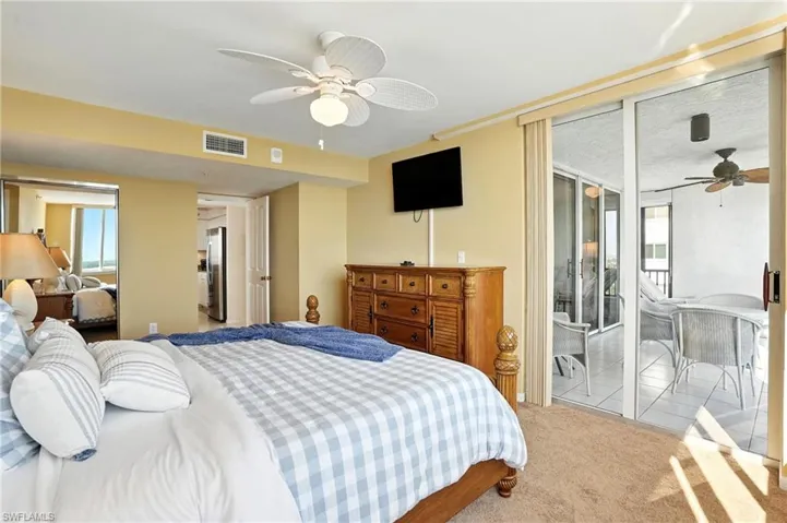 Bedroom featuring beige carpet, and a ceiling fan with access to balcony - Virtually Edited Image
