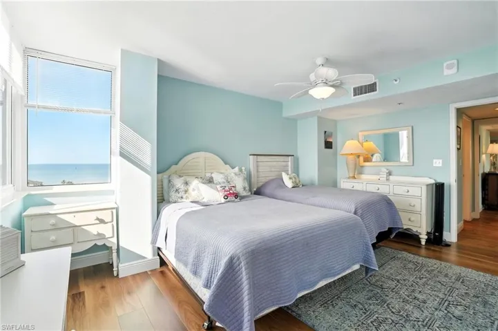 Bedroom featuring wood finished floors, ceiling fan, and a water view - Virtually Edited Image