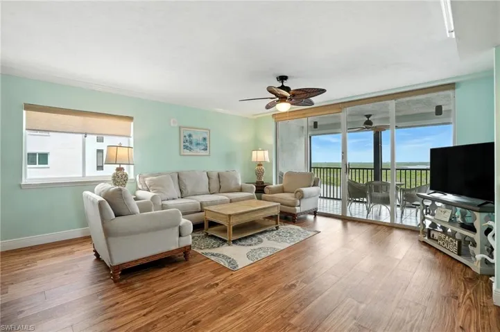 Living room featuring furniture and wood grain floors and bay views. Virtually Edited Photo.