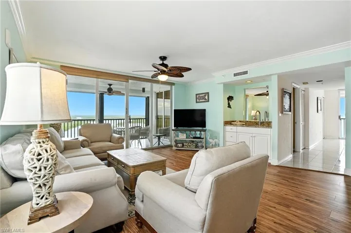 Living room featuring furniture, wood grain floors, ceiling fan and bay view.  Virtually Edited photo.