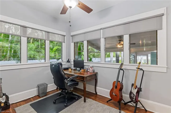 Office area with a ceiling fan and dark wood-style flooring