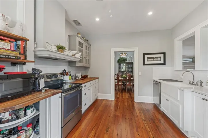 Kitchen with stainless steel appliances, dark wood-style flooring, glass insert cabinets, recessed lighting, and decorative backsplash