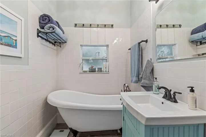 Bathroom with tile walls, a freestanding bath, and vanity