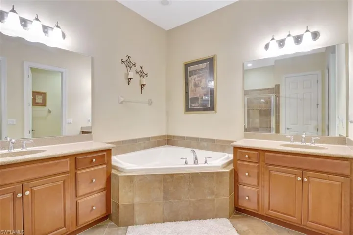 Bathroom with tile floors, dual bowl vanity, and tiled tub