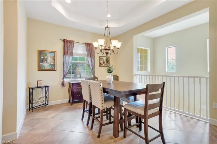 Dining area featuring a raised ceiling, an inviting chandelier, light tile flooring, and a wealth of natural light