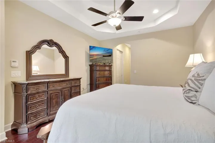Bedroom featuring a raised ceiling, ceiling fan, and dark hardwood / wood-style flooring