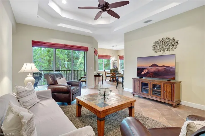 Tiled living room with a raised ceiling and ceiling fan