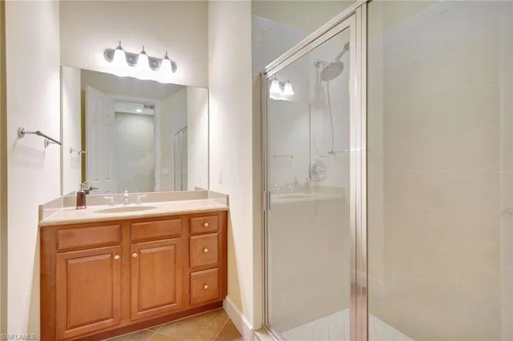 Bathroom featuring a shower with door, tile flooring, and vanity with extensive cabinet space
