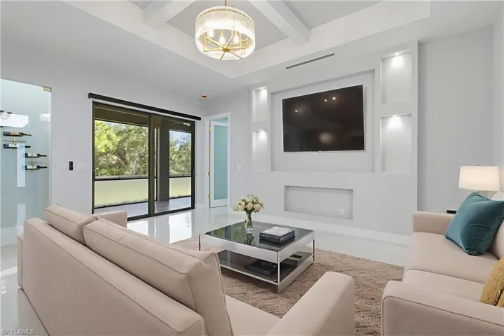 Living room with beamed ceiling, coffered ceiling, and a chandelier