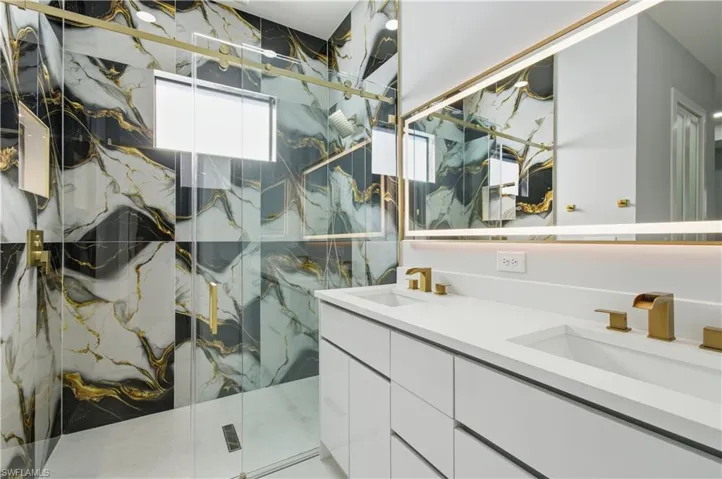 Bathroom with a marble finish shower and double vanity