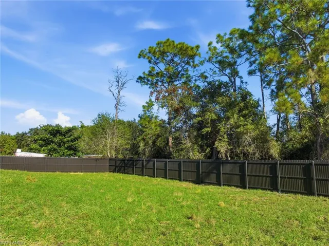 Fenced backyard with view of wooded area