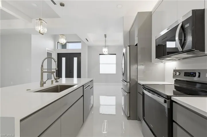 Kitchen with appliances with stainless steel finishes, modern cabinets, pendant lighting, and gray cabinetry
