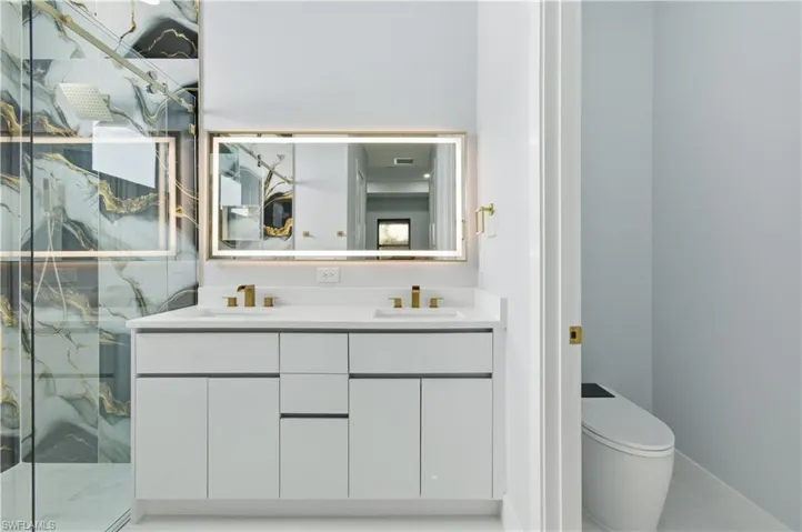 Full bath featuring double vanity and a marble finish shower