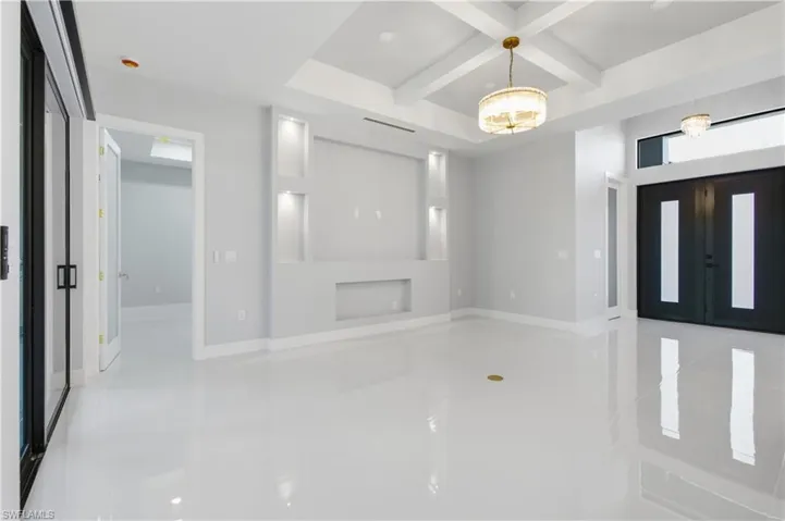 Foyer entrance featuring coffered ceiling, beamed ceiling, a chandelier, light tile patterned floors, and recessed lighting